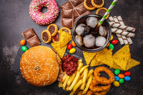 垃圾食品的概念 不健康的食物背景 快餐和糖 巧克力 甜甜圈 苏打水在黑暗的背景 — 图库照片