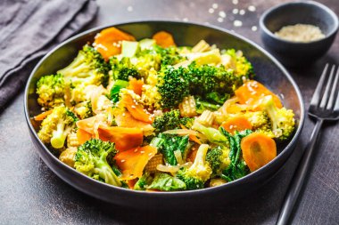 Vegan wok stir fry brokoli ve havuç siyah tabak, karanlık backgrond.