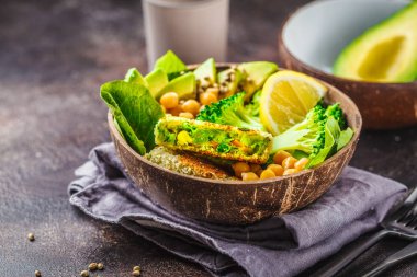 Vegan yemek bir Hindistan cevizi kase: yeşil salata ve nohut ile hamburger. Sağlıklı vegan gıda kavramı.