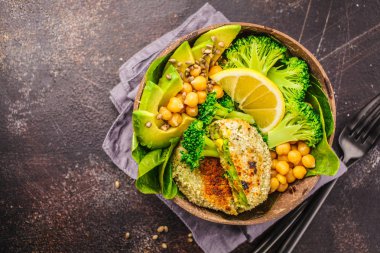 Vegan yemek bir Hindistan cevizi kase: yeşil salata ve nohut ile hamburger. Sağlıklı vegan gıda kavramı.