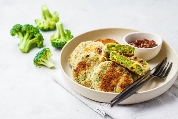 Green Veggie Cutlets in white dish with tomato sauce on white background. Healthy vegn food concept.