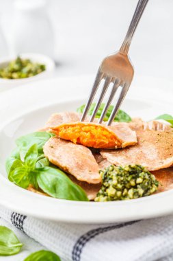 Beyaz bir tabak içinde pesto soslu kabak mantı. Sağlıklı vegan gıda kavramı.