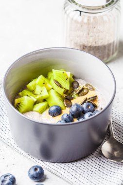 Vejetaryen kahvaltı. Chia puding kivi, yaban mersini ve gri bir kase fıstık ezmesi ile.