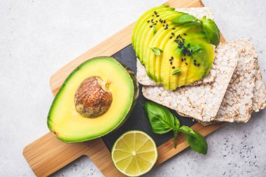 Ahşap masa, beyaz arka plan üzerinde bütün tahıl ekmeği ile avokado tost.