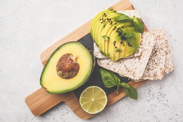 Avocado toast with whole grain bread on a wooden board, white background.