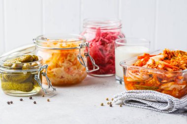 Probiotics food concept. Kimchi, beet sauerkraut, sauerkraut, kefir and pickled cucumbers in glass jars, white background. clipart