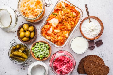 Probiotics food background. Kimchi, beet sauerkraut, sauerkraut, cottage cheese, olives, bread, chocolate, kefir and pickled cucumbers in glass jars, white background, top view. clipart