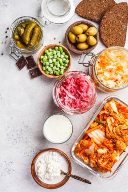 Probiotics food background. Kimchi, beet sauerkraut, sauerkraut, cottage cheese, olives, bread, chocolate, kefir and pickled cucumbers in glass jars, white background, top view. clipart