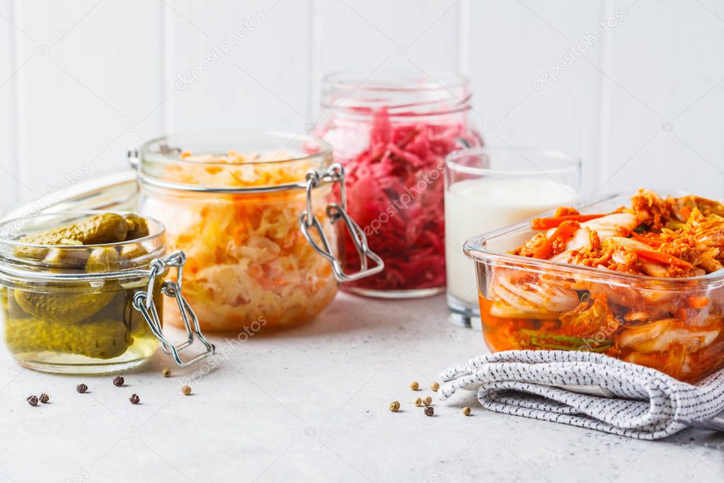 Probiotics food concept. Kimchi, beet sauerkraut, sauerkraut, kefir and pickled cucumbers in glass jars, white background.