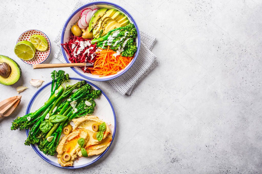 Vegan lunch concept. Rainbow vegetable salad and broccolini with hummus, top view.