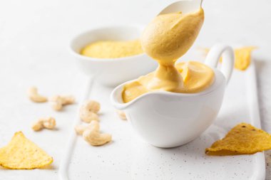 Vegan kaju peynir soslu beyaz sauceboat, beyaz arka planda. Sağlıklı bitki esaslı gıda kavramı.