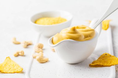 Vegan kaju peynir soslu beyaz sauceboat, beyaz arka planda. Sağlıklı bitki esaslı gıda kavramı.