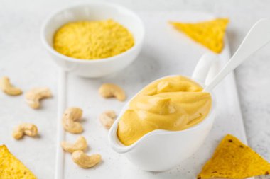 Vegan kaju peynir soslu beyaz sauceboat, beyaz arka planda. Sağlıklı bitki esaslı gıda kavramı.