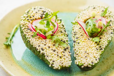 Avokado susam, roka, turp ve yeşil soğan ile dekore edilmiş.