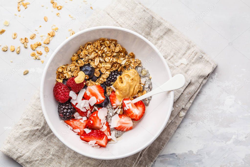 Granola with milk, chia, berries and peanut butter in a white bo