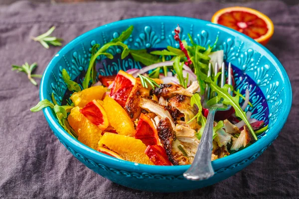 Gegrilde kip en oranje salade met rucola in blauw bord op w — Stockfoto