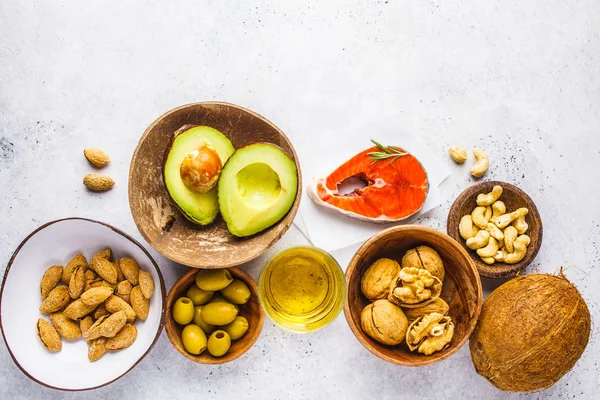 Healthy fat food background. Fish, nuts, oil, olives, avocado on