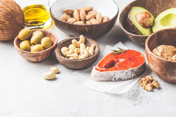 Healthy fat food background. Fish, nuts, oil, olives, avocado on