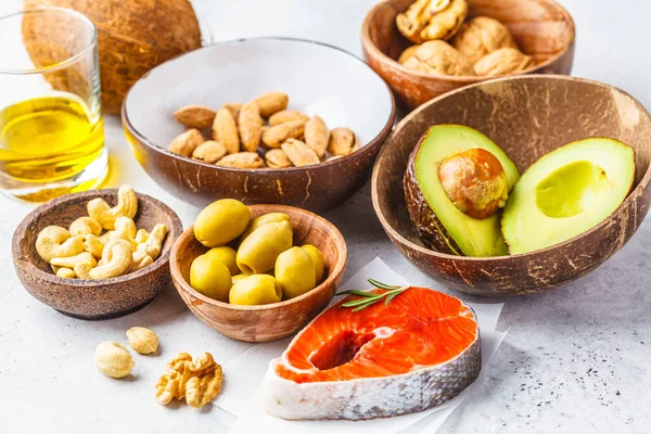 Healthy fat food background. Fish, nuts, oil, olives, avocado on