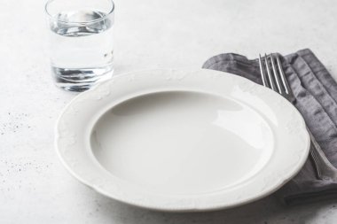 Boş tabak ve bardak su, beyaz arka plan. Tıbbi fastin