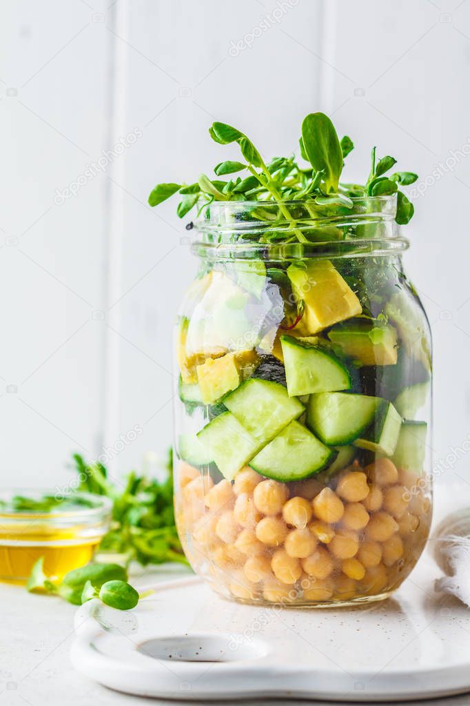 Green salad with chickpeas in a jar, white background, copy spac