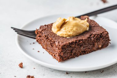 Beyaz PLA üzerinde fıstık ezmesi ile Vegan çikolata Brownie parçası