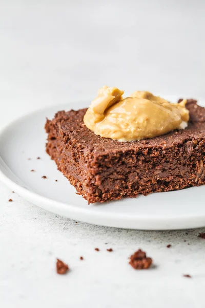 Piece of vegan chocolate brownie with peanut butter on white pla