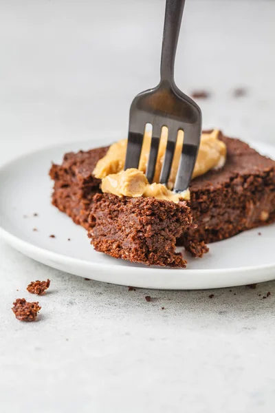 Piece of vegan chocolate brownie with peanut butter on white pla