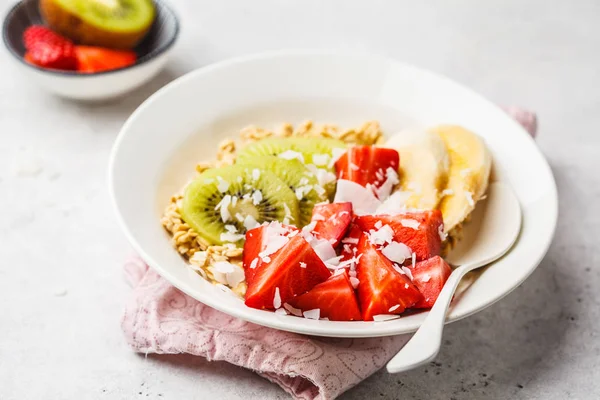 Summer oatmeal with fruit and coconut in white plate. — Stock Photo, Image