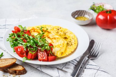 Beyaz tabakta peynir ve domates salatası ile klasik omlet.