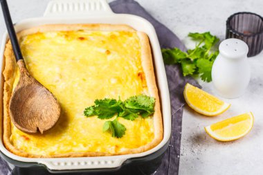 Siyah bir fırın kabında peynir ve yeşillik ile Quiche.