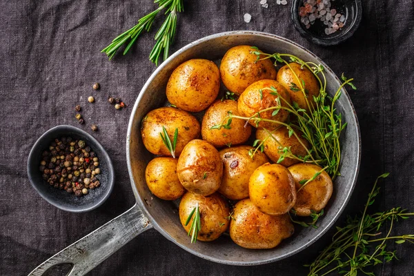 Batatas assadas em uma frigideira de ferro fundido, fundo escuro . — Fotografia de Stock