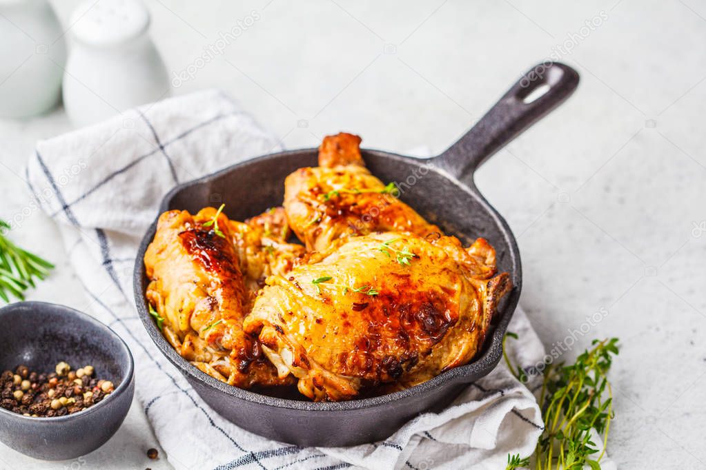 Grilled chicken  in a cast iron skillet, white background.