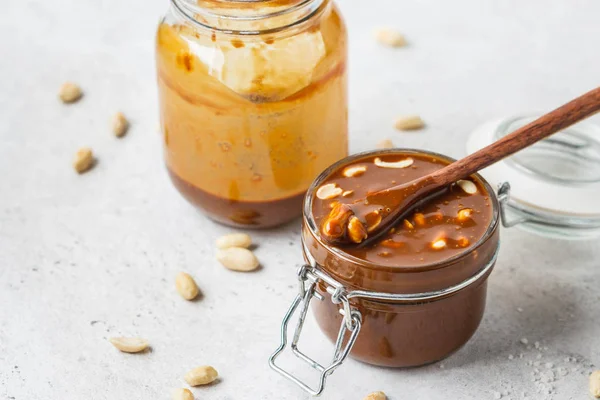 Zelfgemaakte gezouten karamel met noten in glazen pot, kopieer ruimte. — Stockfoto