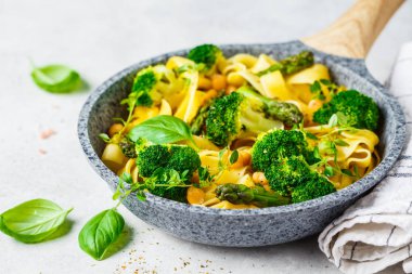 Tavada brokoli, kuşkonmaz ve nohut ile vejetaryen makarna.