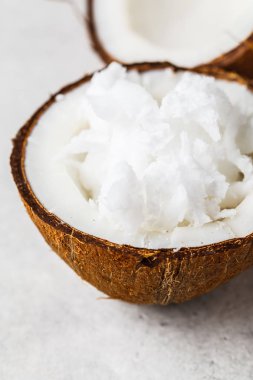 Gri arka planda bir Hindistan cevizi kabuğu içinde Hindistan cevizi yağı.