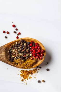 Biber ve ahşap kaşık üzerinde baharatlar, beyaz arka plan.