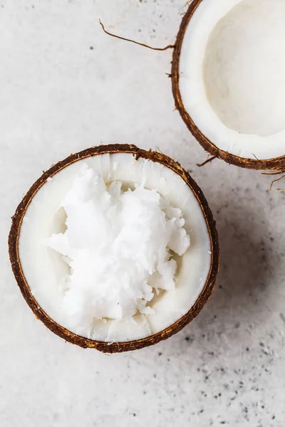 Óleo de coco em casca de coco sobre fundo cinza, vista superior . — Fotografia de Stock