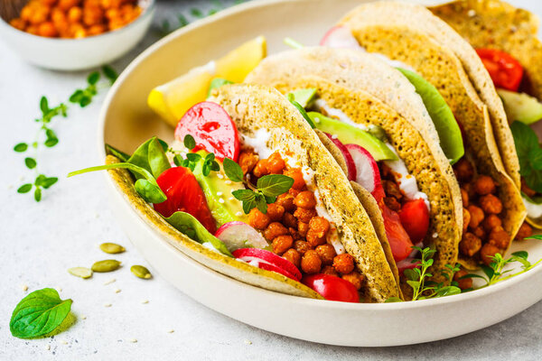 Vegan tacos with baked chickpeas, avocado, sauce and vegetables 