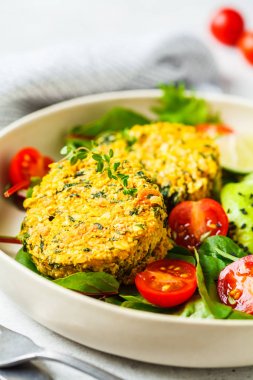 Beyaz bir tabakta salata ile Vegan kabak ve Quinoa pirzola.