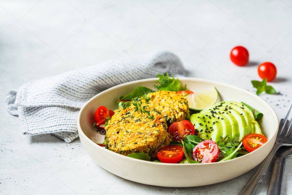 Vegan pumpkin and quinoa cutlets with salad in a white plate.
