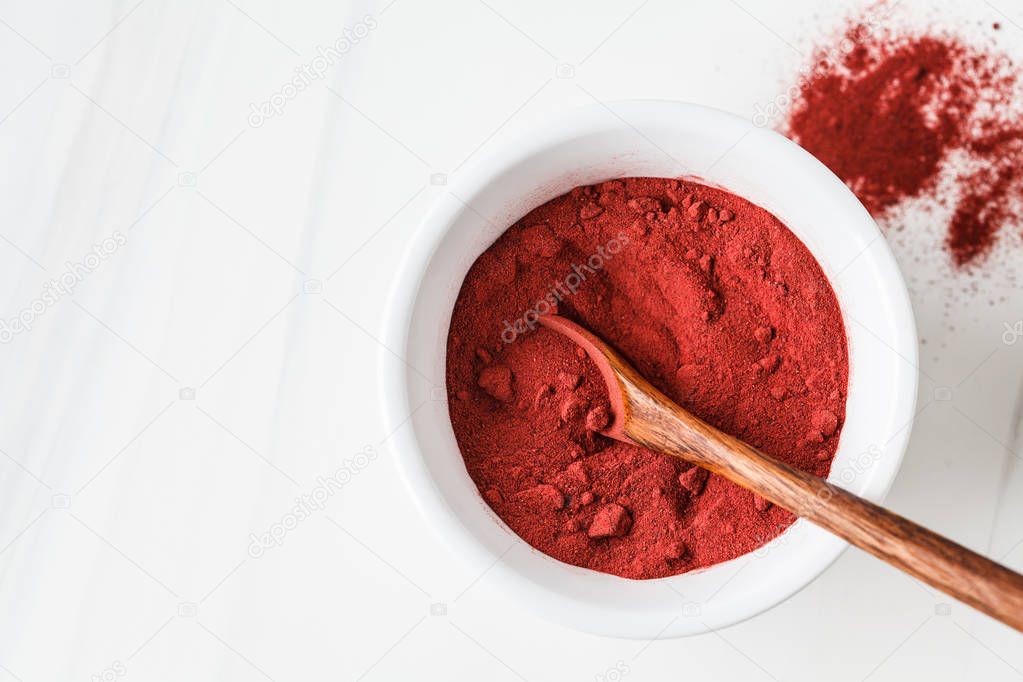 Superfood beetroot powder in white bowl on a white background. 