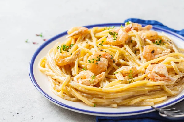 Shrimp pasta with cream and herbs in white plate, copy space.