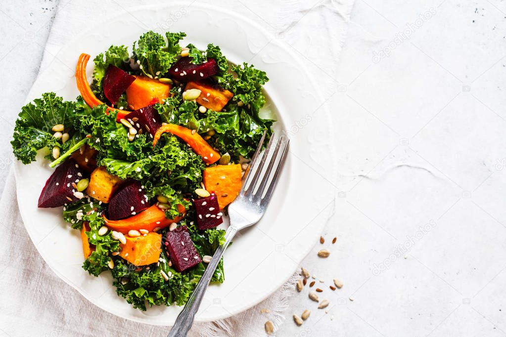 Kale salad with baked vegetables in white plate.