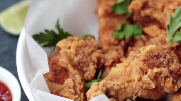 Man eating crispy fried chicken in a white bowl with tomato sauce. — Stock Video