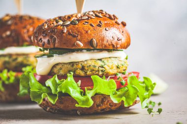 Sebzeli ve soslu vejetaryen falafel burger, koyu arkaplan. Sağlıklı gıda konsepti.