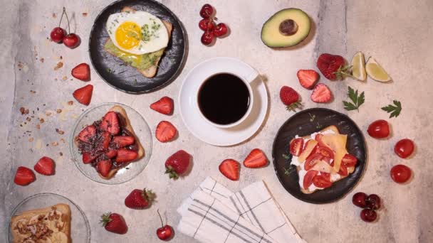 Перемешивание кофе. Завтрак различные тосты с ягодами, сыром, яйцом и фруктами, вид сверху. Концепция завтрака . — стоковое видео