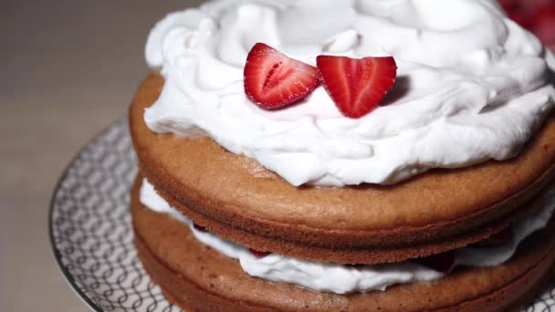 Sommerkekskuchen mit Schlagsahne und Erdbeeren. Kuchen kochen - Dekoration mit Beeren. — Stockvideo