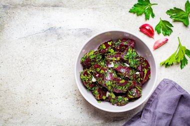 Sarımsaklı pancar salatası ve hafif arka planda gri bir kasede otlar..