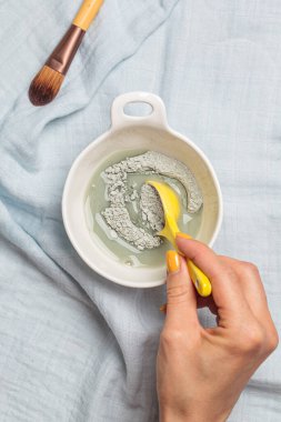 Kil yüz maskesi hazırlıyorum. Kuru kille suyu karıştırıyorum. Cilt bakımı kavramı.